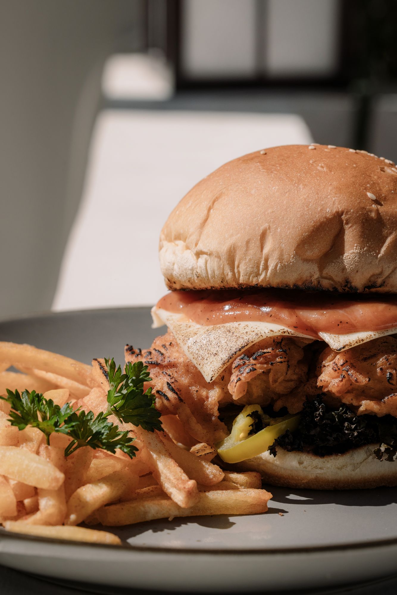 Bonnie’s burger with a crisp patty and melted cheese, fries alongside, in hard afternoon light.