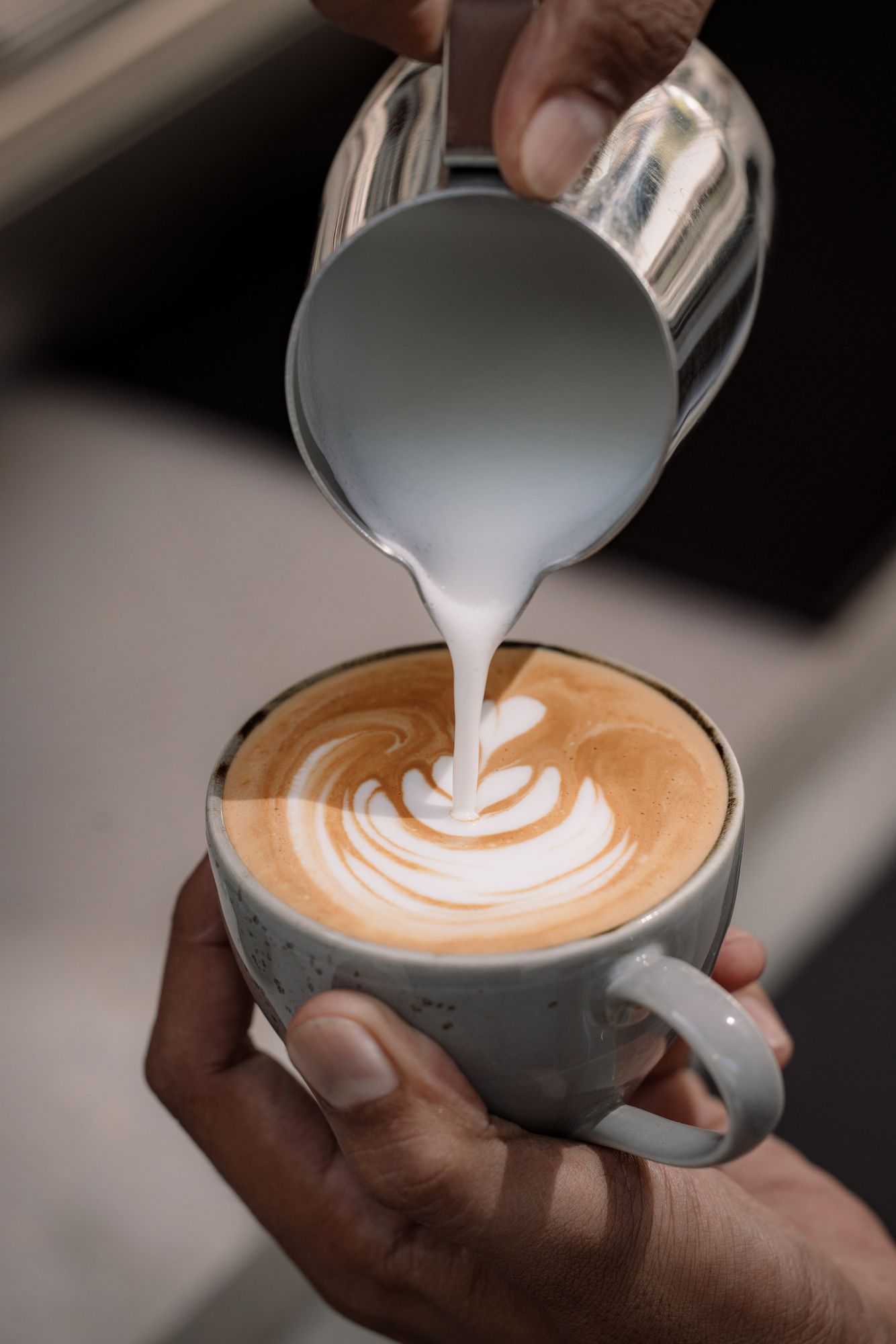 Milk poured into a latte, a rosetta forming in the cup.