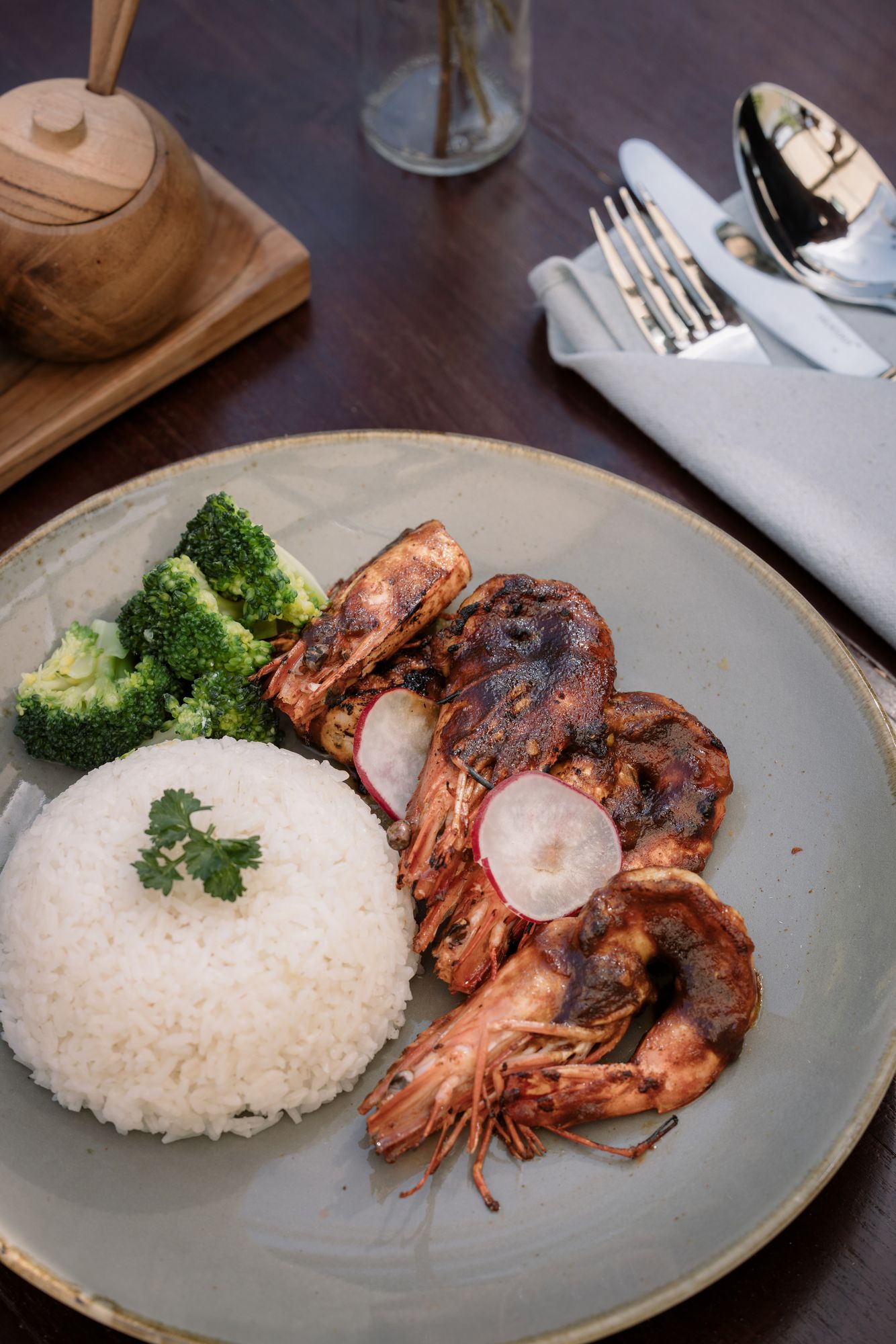 Grilled king prawns glazed in sambal beside a dome of white rice and broccoli.